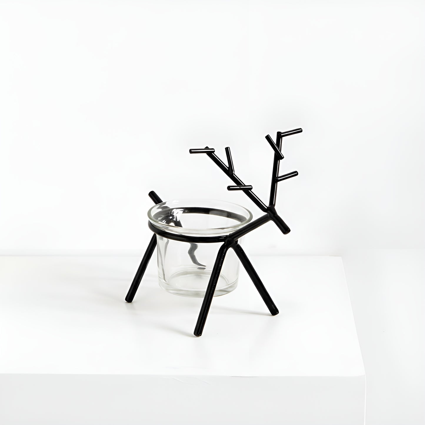 Black deer-shaped candle holder with a glass base on a white background