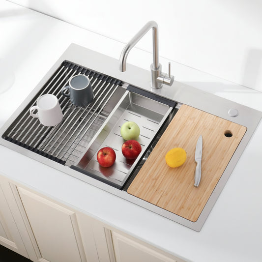 Stainless steel kitchen sink with a cutting board and fruits on a white countertop
